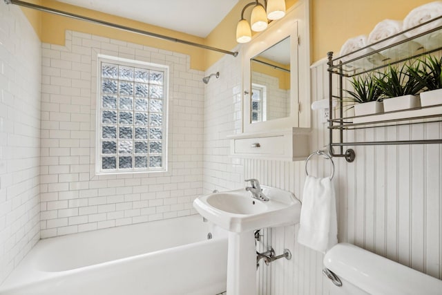 bathroom featuring toilet and tiled shower / bath