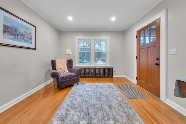 entrance foyer with hardwood / wood-style flooring, radiator heating unit, and crown molding