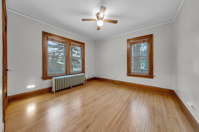 spare room featuring light wood-type flooring, ceiling fan, radiator, and crown molding