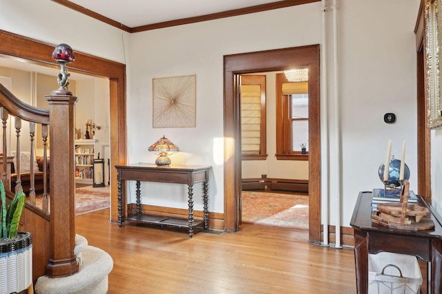 hallway with baseboard heating, ornamental molding, and light hardwood / wood-style floors