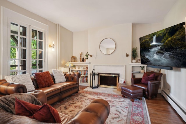 living room featuring a brick fireplace, a baseboard heating unit, and hardwood / wood-style floors