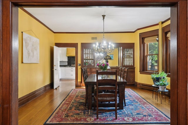 dining area with crown molding, dark hardwood / wood-style floors, an inviting chandelier, and baseboard heating