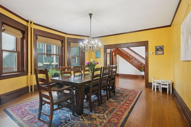 dining area featuring crown molding, wood-type flooring, an inviting chandelier, and baseboard heating