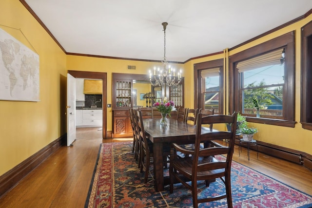 dining space featuring an inviting chandelier, crown molding, and dark hardwood / wood-style floors