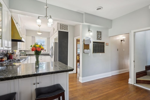 kitchen with pendant lighting, white cabinets, dark hardwood / wood-style flooring, kitchen peninsula, and stainless steel appliances