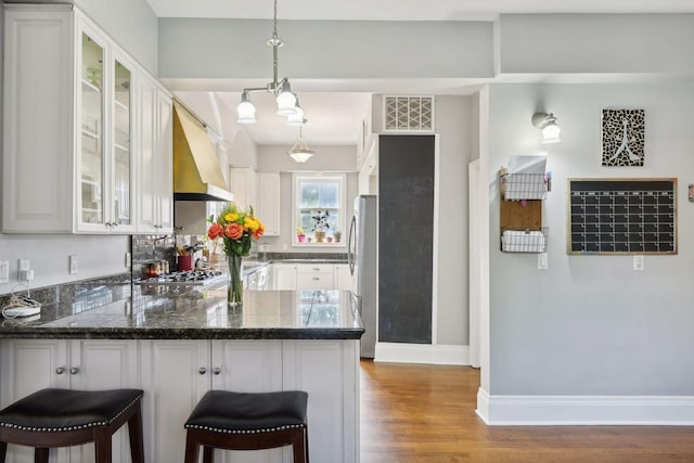 kitchen with white cabinetry, custom range hood, pendant lighting, and kitchen peninsula