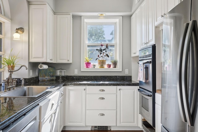 kitchen with double oven, refrigerator, sink, and white cabinets