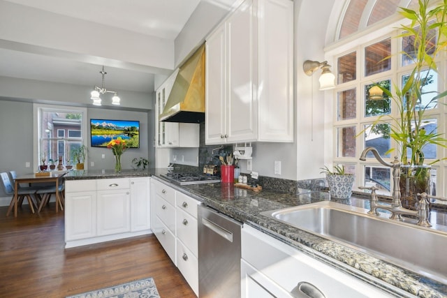 kitchen with wall chimney exhaust hood, sink, decorative light fixtures, appliances with stainless steel finishes, and white cabinets