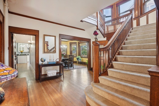 stairs featuring wood-type flooring and crown molding