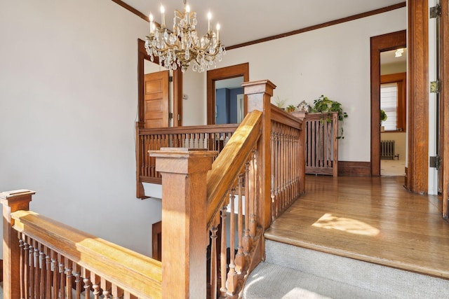 stairway featuring hardwood / wood-style flooring, ornamental molding, radiator heating unit, and a notable chandelier