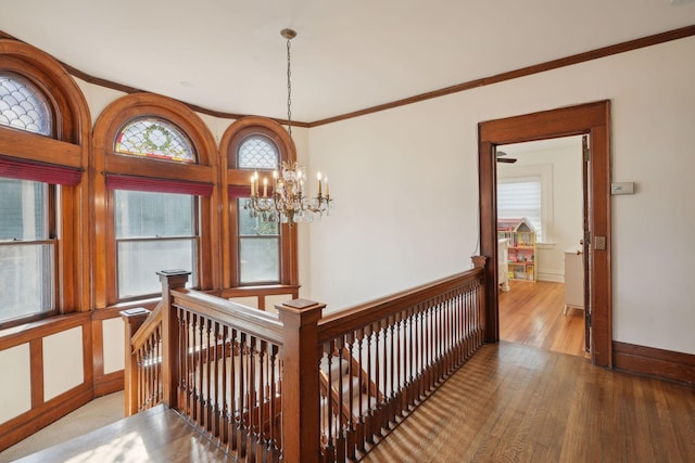 hallway featuring hardwood / wood-style floors, crown molding, a chandelier, and a healthy amount of sunlight