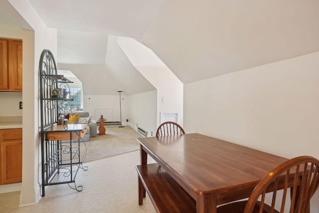 dining space with a baseboard radiator, lofted ceiling, and light carpet