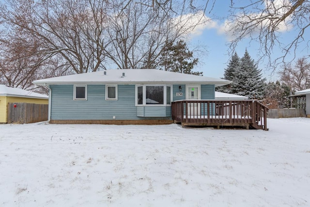 snow covered back of property with a wooden deck