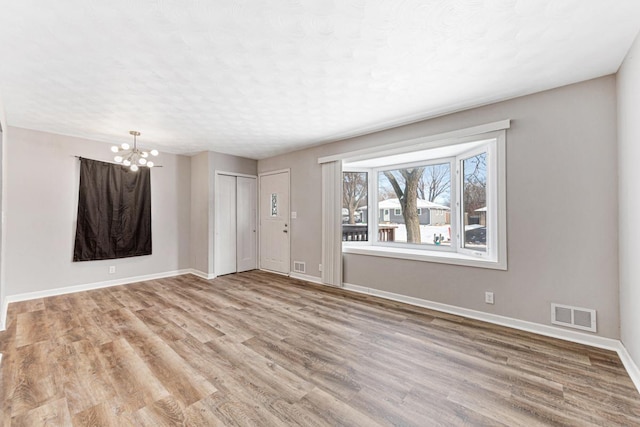 spare room featuring light hardwood / wood-style floors and an inviting chandelier