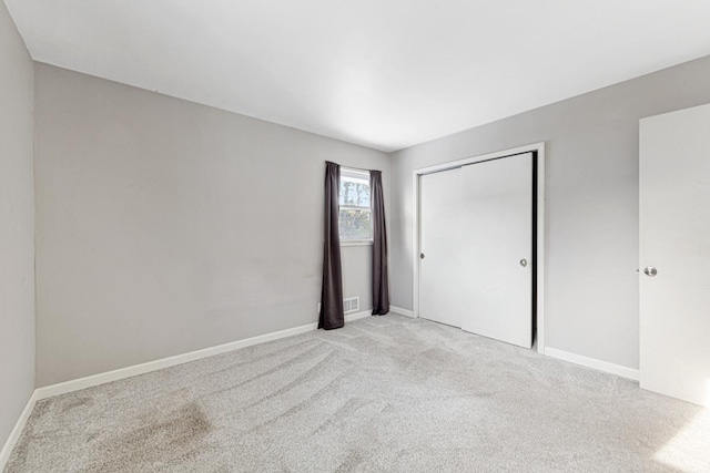 unfurnished bedroom featuring light colored carpet and a closet