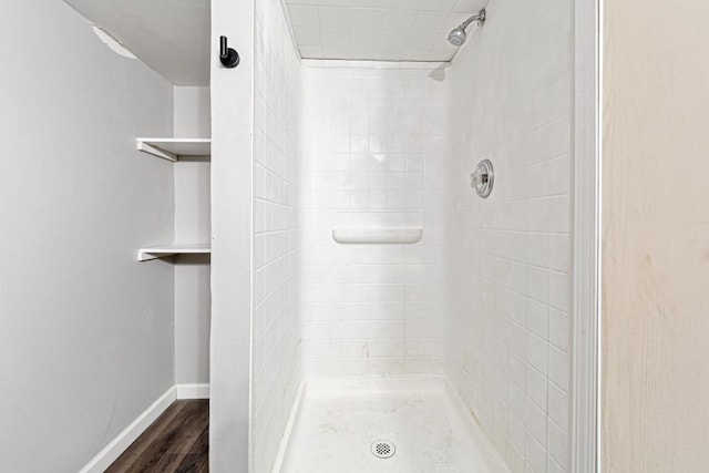 bathroom with tiled shower and wood-type flooring