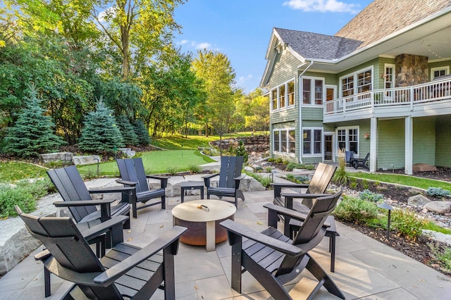 view of patio featuring a balcony and an outdoor fire pit