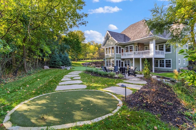 rear view of property featuring a patio, a balcony, and a lawn