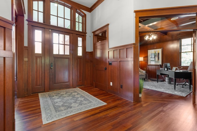 foyer entrance with an inviting chandelier, ornamental molding, and dark wood-type flooring