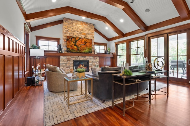 living room with wood-type flooring, a stone fireplace, a wealth of natural light, and high vaulted ceiling