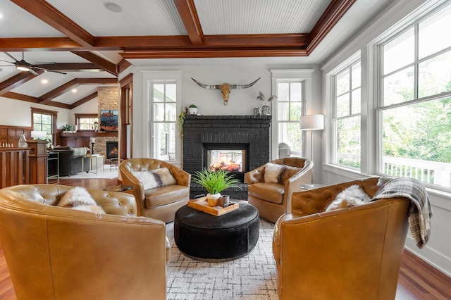 living room with lofted ceiling with beams, wood-type flooring, a brick fireplace, and ceiling fan