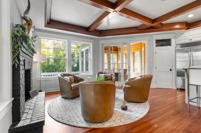 sitting room featuring ornamental molding, a brick fireplace, coffered ceiling, and hardwood / wood-style floors