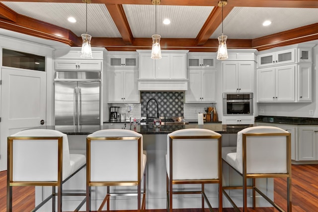 kitchen with a center island, hanging light fixtures, dark stone counters, stainless steel appliances, and white cabinets