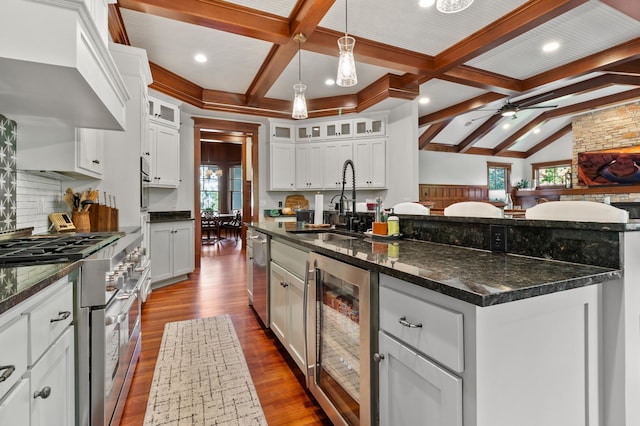 kitchen with white cabinetry, stainless steel appliances, a spacious island, wine cooler, and dark stone counters