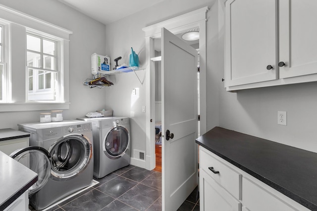 laundry area featuring dark tile patterned floors, cabinets, and independent washer and dryer