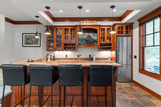 bar with crown molding, hanging light fixtures, a tray ceiling, and stainless steel refrigerator