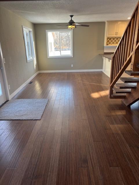 unfurnished living room featuring a textured ceiling, ceiling fan, and dark hardwood / wood-style flooring