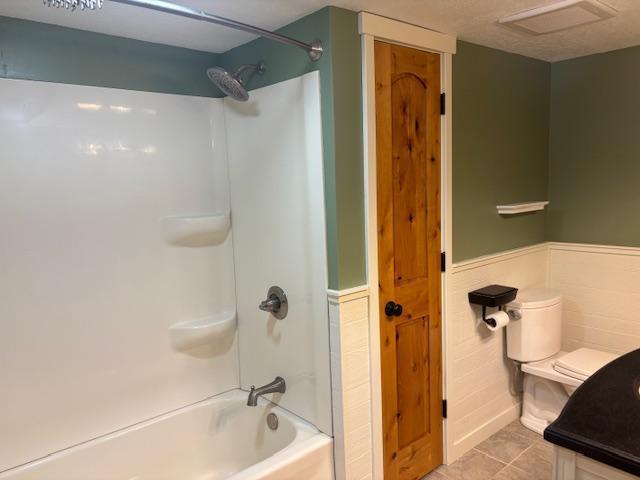 full bathroom featuring shower / bathing tub combination, tile patterned flooring, vanity, tile walls, and toilet