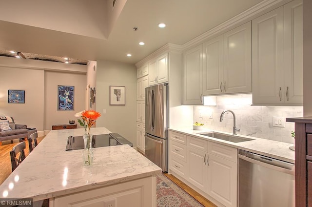 kitchen with white cabinetry, appliances with stainless steel finishes, light stone countertops, and sink