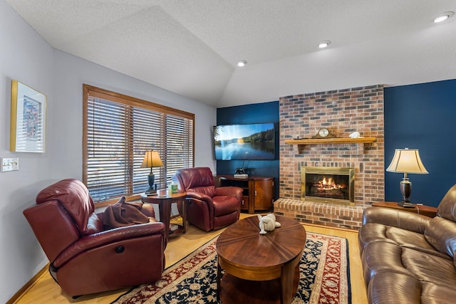 living room featuring a brick fireplace, vaulted ceiling, light hardwood / wood-style floors, and a textured ceiling