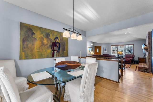 dining room with lofted ceiling, a textured ceiling, and light wood-type flooring