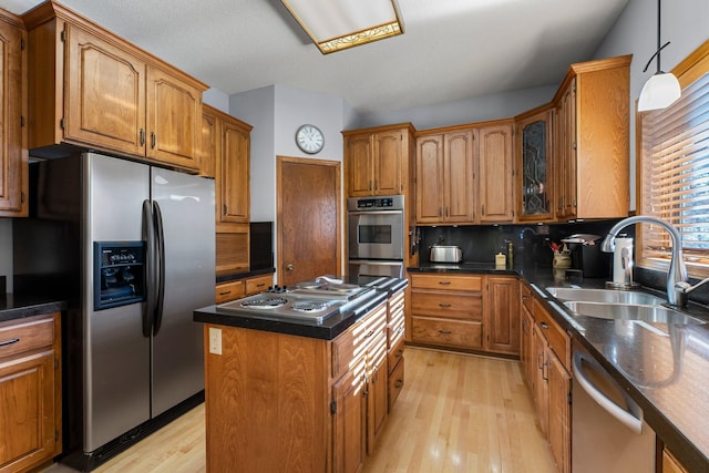 kitchen featuring sink, appliances with stainless steel finishes, backsplash, a center island, and light wood-type flooring