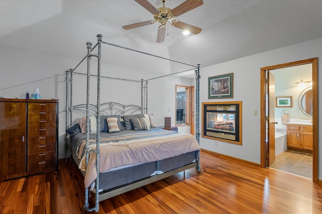 bedroom with connected bathroom, a textured ceiling, hardwood / wood-style floors, and ceiling fan