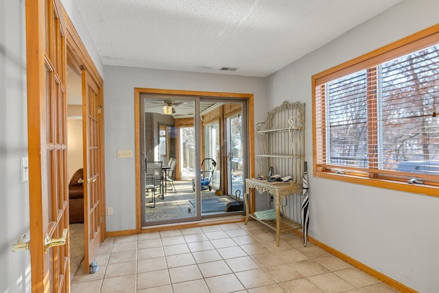 doorway with light tile patterned flooring and a textured ceiling