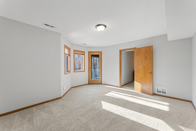 carpeted empty room featuring a textured ceiling