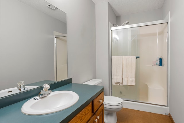 bathroom featuring vanity, a textured ceiling, a shower with door, and toilet