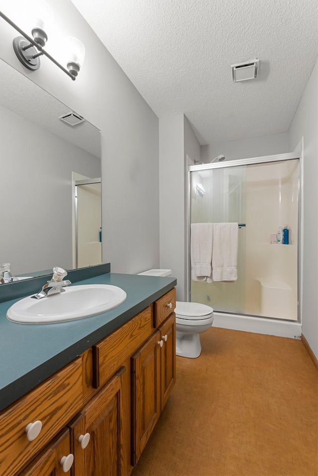 bathroom with vanity, a textured ceiling, a shower with shower door, and toilet