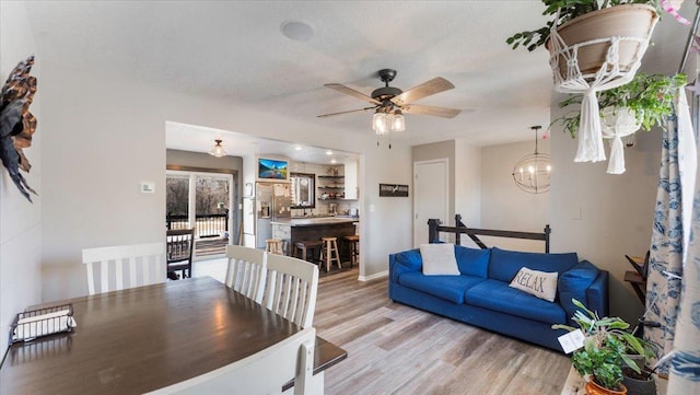 living room with a textured ceiling, light hardwood / wood-style floors, and ceiling fan