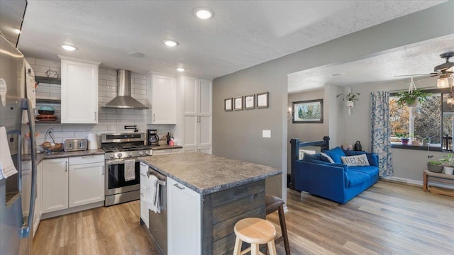 kitchen with white cabinetry, wall chimney exhaust hood, stainless steel appliances, and light wood-type flooring