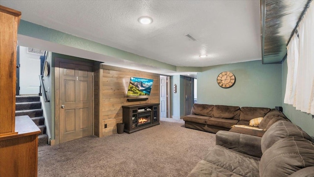 carpeted living room featuring wooden walls and a textured ceiling