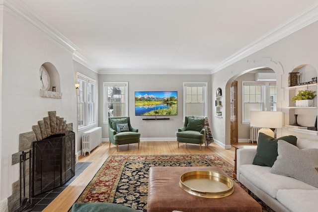 living room featuring radiator, crown molding, wood-type flooring, and an AC wall unit