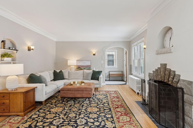 living room with ornamental molding, radiator, and light wood-type flooring