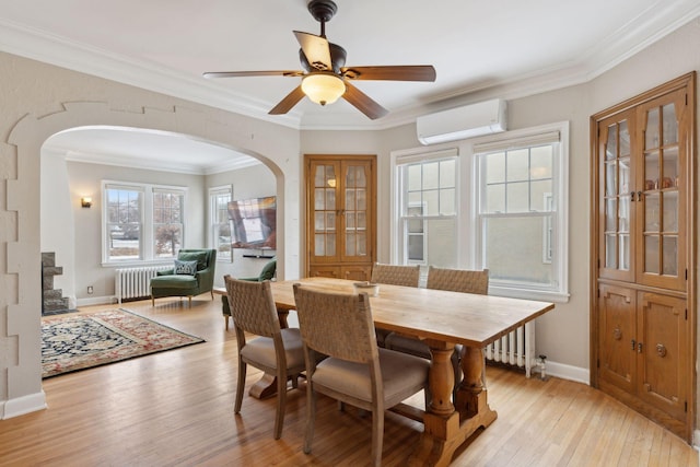 dining room featuring ceiling fan, radiator heating unit, a wall unit AC, ornamental molding, and light hardwood / wood-style floors