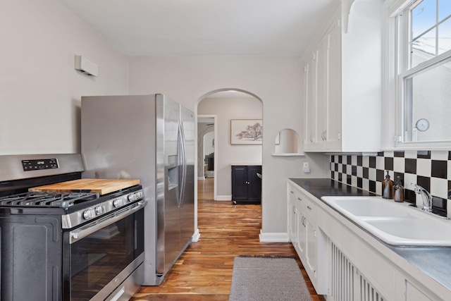 kitchen with gas range, sink, light hardwood / wood-style flooring, and white cabinets