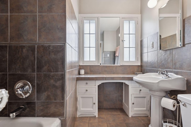 full bathroom with plus walk in shower, sink, tile walls, toilet, and tile patterned floors