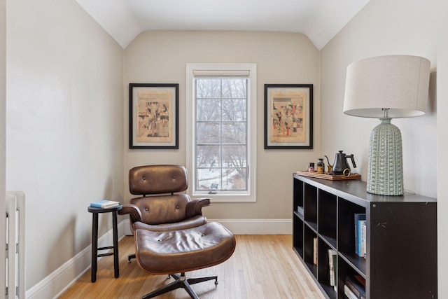 sitting room with hardwood / wood-style floors, a wealth of natural light, lofted ceiling, and radiator heating unit